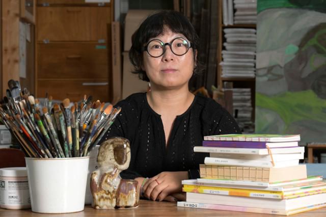 내 그림의 베이스는 문학이라는 노석미 작가가 붓과 자신의 펴낸 책들과 함께 포즈를 취하고 있다. 강예진 기자