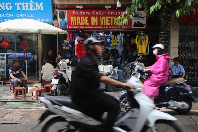 3일 베트남 하노이의 한 거리에서 오토바이를 탄 시민들이 '메이드 인 베트남' 매장 앞을 지나고 있다. 하노이=EPA 연합뉴스