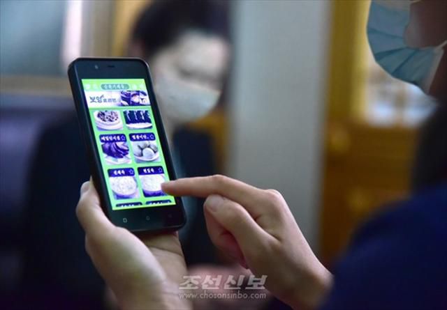 요리 애플리케이션 화면 보고있는 북한 주민. 평양=조선신보 연합뉴스