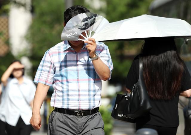 폭염이 계속되는 10일 서울 종로구 거리에서 시민들이 부채와 양산으로 햇볕을 피하며 걸어가고 있다. 뉴시스