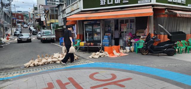 18일 오후 광주 상습 침수 지역인 남구 백운광장 주변 주택가에서 재난 당국 관계자들이 폭우에 대비해 상가 앞에 모래주머니를 쌓고 있다.