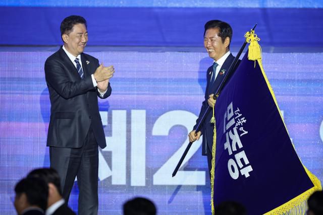 정청래(오른쪽) 더불어민주당 신임 당대표가 2일 경기 고양시 킨텍스에서 열린 제2차 임시전국당원대회에서 김병기 원내대표로부터 당기를 이양받고 있다. 뉴시스