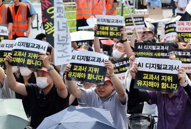 한국교과서협회 회원들이 지난달 21일 오전 서울 영등포구 여의도 국회의사당역 앞에서 열린 초·중등교육법 개정안 규탄 집회에서 AI 디지털교과서(AIDT)의 교과서 지위 유지를 촉구하고 있다. 뉴스1