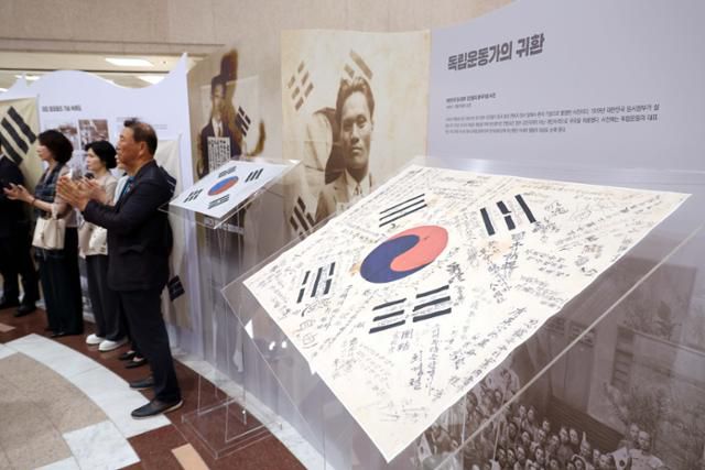 전시회 참석자들이 18일 국회 도서관 로비에서 열린 '광복80주년 국회 특별전 오늘 다시 보았네, 우리 태극기 전시회'에서 박수를 치고 있다. 뉴시스
