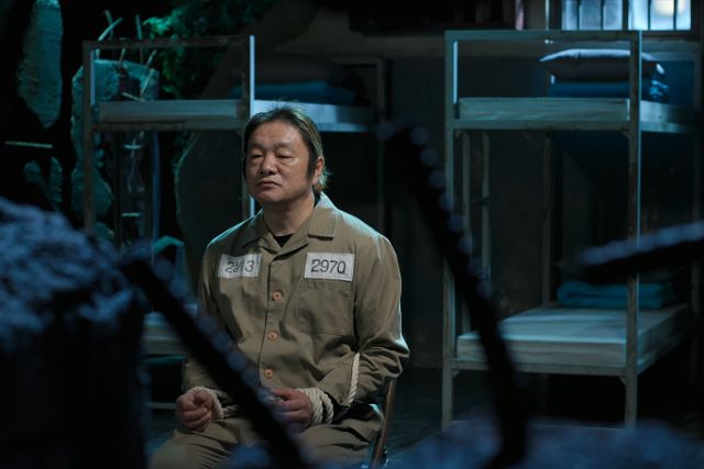 형제복지원에 자신을 넘겼던 경찰에 대한 트라우마로 경찰만 보면 폭언 등을 해 전과 36범이 된 생존자 최승우씨가 형제복지원을 복원한 세트장에서 죄수복을 입고 포승줄에 묶인 채 인터뷰하고 있다. 넷플릭스 캡처