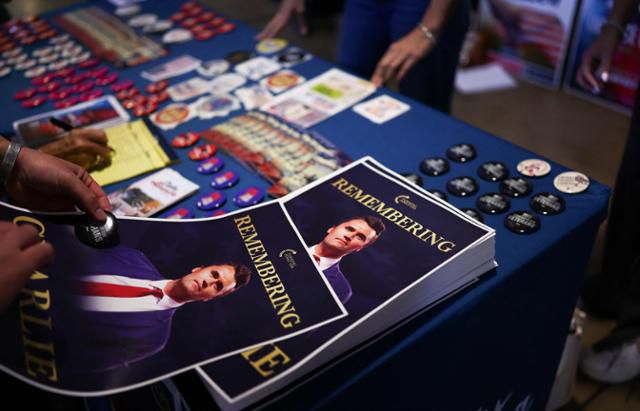 미국 애리조나주 템피의 애리조나 주립대학교 캠퍼스 데저트 파이낸셜 아레나에서 15일 우익 활동가 찰리 커크를 추모하는 집회가 열린 가운데 참석자들이 전단지와 버튼을 들고 있다. 템피=AFP 연합뉴스