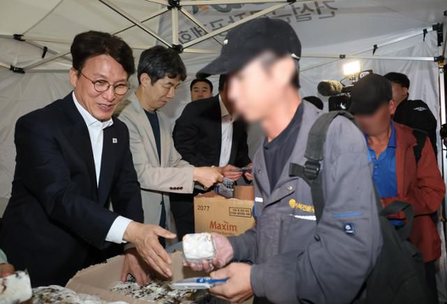 김민석 국무총리가 10일 서울 구로구 남구로 새벽인력시장을 찾아 근로자들에게 떡을 나눠주고 있다. 연합뉴스