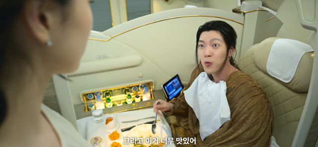 드라마 '다 이루어질지니'에서 지니 역을 맡은 김우빈(오른쪽)이 비행기 기내식을 먹으며 이거 너무 맛있어라고 말하고 있다. 이 기내식 서비스를 제공하는 아랍에미리트 항공사인 에미레이트가 간접광고(PPL) 투자사로 참여했다. 넷플릭스 오리지널 드라마에서 대사를 통해 노골적인 PPL이 노출되기는 이례적이다. 넷플릭스 영상 캡처