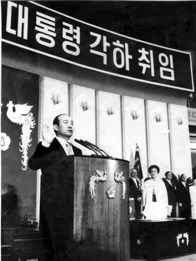 전두환이 1981년 3월 3일 잠실실내체육관에서 열린 제12대 대통령 취임식에서 선서하는 모습. 오른쪽에 서서 그를 바라보는 사람은 부인인 이순자(흰옷 입은 여성)다. 전두환은 1980년 8월, 유신헌법에 따라 11대 대통령으로 취임한 뒤 헌법을 고쳐 이듬해 12대 대통령으로 재차 취임했다.