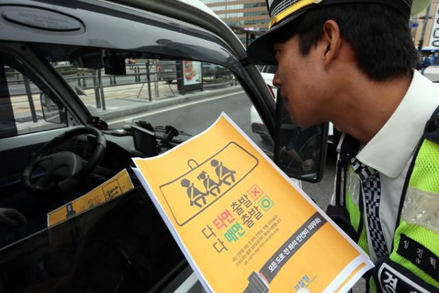 개정된 도로교통법이 시행되며 전 좌석 안전띠 착용이 의무화된 2018년 10월 서울 세종로사거리에서 교통경찰이 홍보전단을 배포하고 있다. 류효진 기자