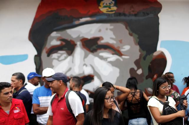 베네수엘라 카라카스의 대통령궁 앞에서 2019년 5월 니콜라스 마두로 대통령 재선 1주년 기념 친정부 집회가 열린 가운데 친정부 지지자들이 고(故) 우고 차베스 전 베네수엘라 대통령 벽화 앞에 모여 있다. 카라카스=로이터 연합뉴스