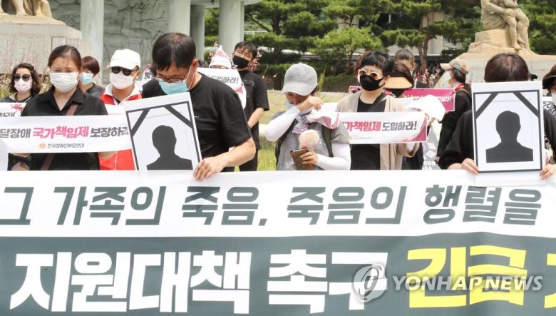 지난 6월 10일 청와대 분수대 앞에서 열린 발달장애인 가족 보건복지부 규탄 및 지원대책 촉구 긴급 기자회견에서 한 참석자가 6월 3일 광주에서 사망한 발달장애인과 가족의 추모사를 시작하자 많은 참석자들이 눈물을 흘리고 있다. [연합]