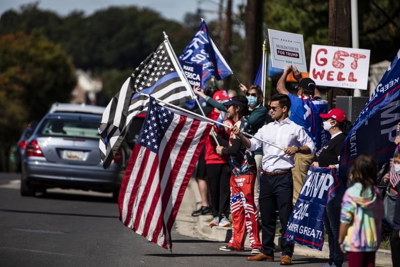 도널드 트럼프 미국 대통령이 신종 코로나바이러스 감염증(코로나19)으로 입원한 메릴랜드주 베데스다의 월터 리드 군 병원 앞에서 3일(현지시간) 지지자들이 트럼프 대통령의 쾌유를 기원하며 피켓과 성조기 등을 들고 모여 있다. [연합]