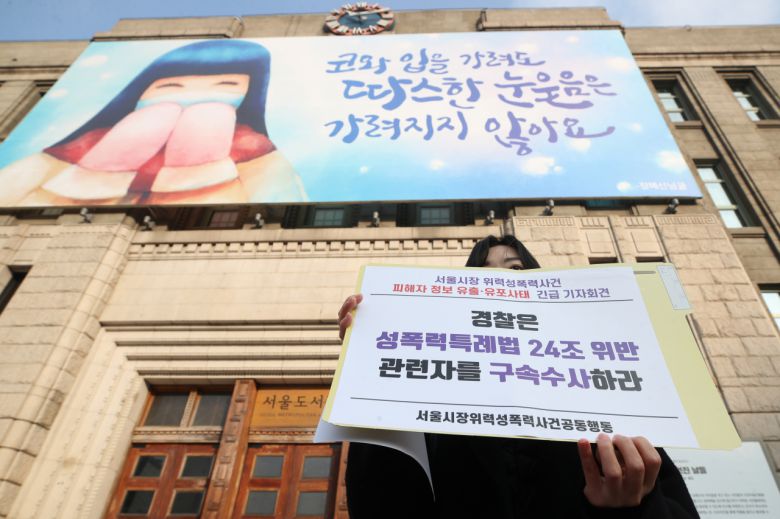 서울시장위력성폭력사건공동행동이 지난 28일 오전 서울 중구 서울시청 앞에서 '서울시장 위력성폭력 사건 피해자 정보 유출·유포 사태 긴급 기자회견'을 하고 있는 가운데 한 관계자가 손팻말을 들고 있다. [연합]