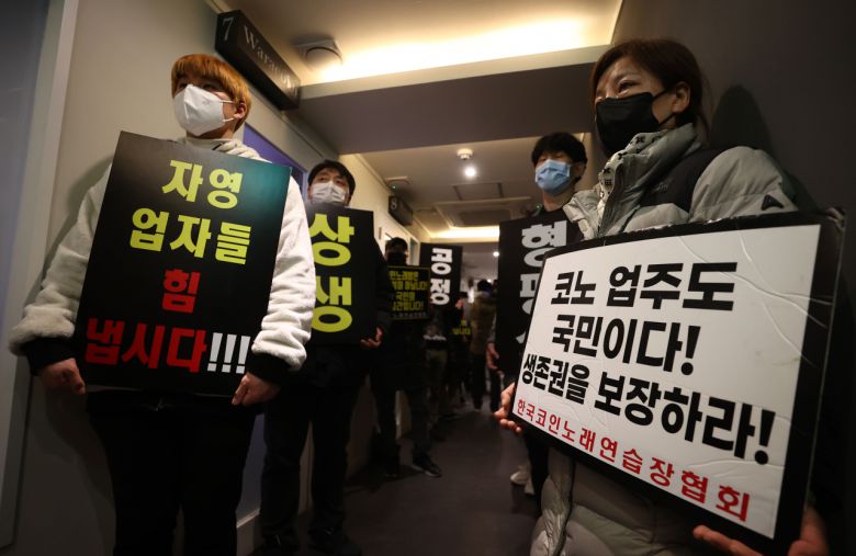 9일 자정 서울 서대문구의 한 코인노래방에서 코로나19 대응 전국자영업자 비상대책위 주최로 열린 방역기준 불복 개점 시위에서 참석자들이 정상 영업을 촉구하며 구호를 외치고 있다. 이날 시위에서 코인노래방 업주들은 방역 당국의 획일적인 영업시간 제한 폐지, 형평성 있는 방역기준 조정과 대책 마련을 촉구했다. [연합]