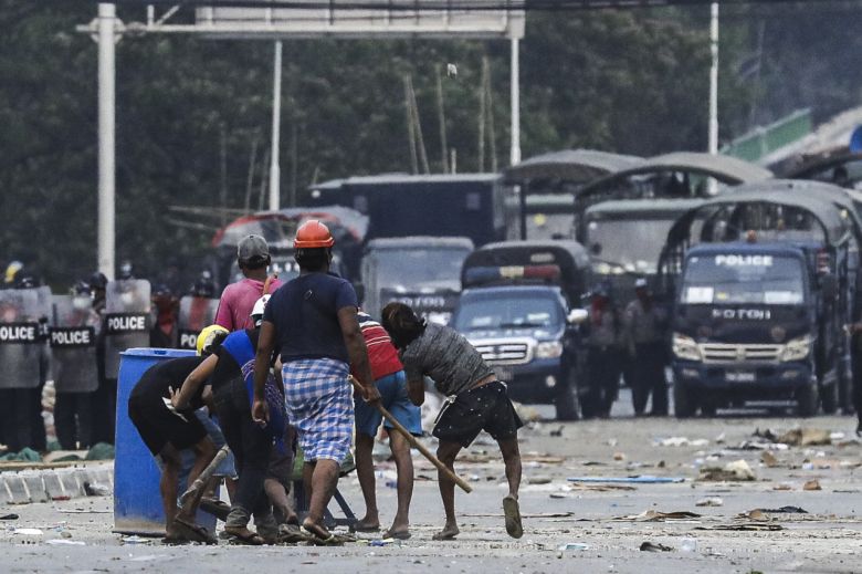 14일(현지시간) 미얀마 최대 도시 양곤에서 반(反) 쿠데타 시위에 참가한 사람들이 진압을 위해 출동한 군경을 향해 돌을 던지고 있다. [EPA]
