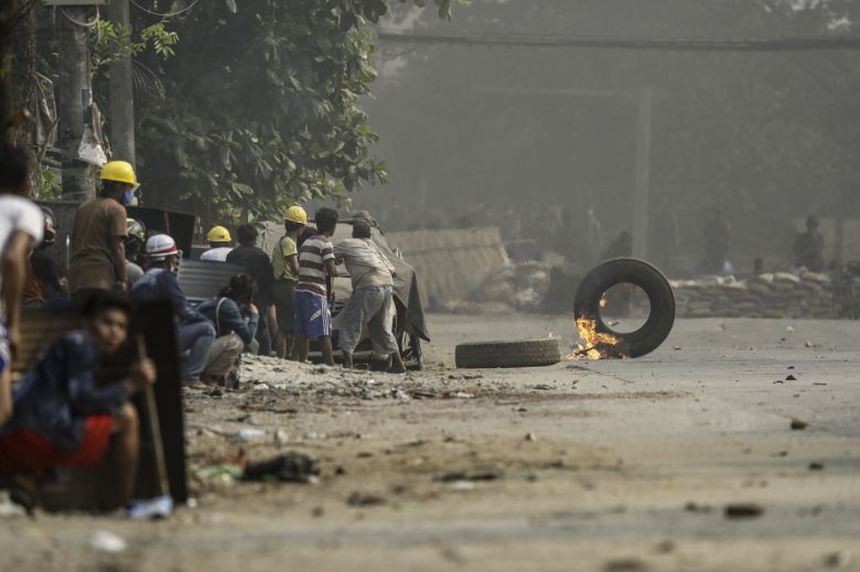 14일(현지시간) 미얀마 최대 도시 양곤에서 쿠데타에 반대하는 시위대가 진압을 위해 출동한 군경이 쏘는 최루탄과 실탄 등을 피하기 위해 몸을 숨기고 있다. [EPA]