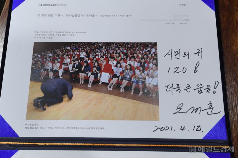 12일 ‘120다산콜재단’을 방문한 오세훈 서울시장이 11년 전 120다산콜센터 출범 당시 찍은 사진첩 등 옛 기록들을 받고 사인했다. [서울시 제공]