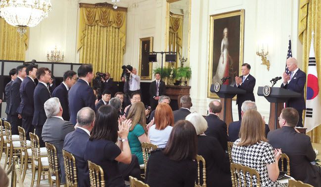 문재인 대통령의 3박5일 방미 일정의 성과를 보여주는 두 장의 사진이다. 문 대통령이 방미 중인 21일 백악관 이스트룸에서 열린 한국전쟁 명예 훈장 수여식서 조 바이든 미국 대통령, 랠프 퍼켓 주니어 예비역 대령 가족과 기념촬영을 하고 있다. 문 대통령은 이날 행사 참석을 통해 양국 관계의 바탕이 ‘안보동맹’에 있음을 재확인하고, 혈맹의 우의를 굳건히 했다.(위쪽 사진) 이어 열린 정상회담 후 공동기자회견에서 바이든 미 대통령이 문 대통령이 보는 앞에서 최태원 SK그룹 회장(왼쪽) 등 경제사절단 기업 대표들을 일으켜 세워 감사 박수를 보내고 있다. 이는 ‘경제동맹’으로서 양국간 관계 발전을 보여주는 상징적 장면이 됐다. [연합]