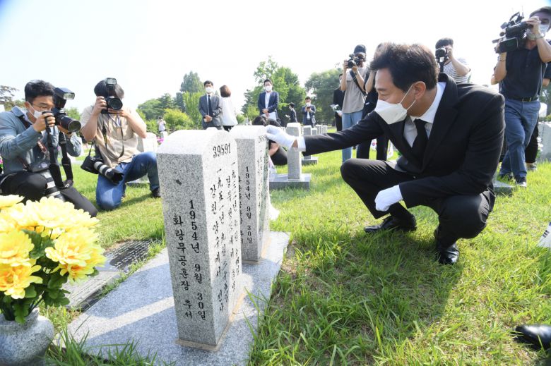 오세훈 서울시장이 6.25 전쟁 71주년을 맞은 25일 오전 9시 군 복무 중 사고를 당한 청년유공자인 하재헌 조정선수, 이주은 해병대위, 모델 이찬호씨와 함께 국립서울현충원을 참배한 후 한 전사자의 묘비를 쓰다듬고 있다. [서울시 제공]