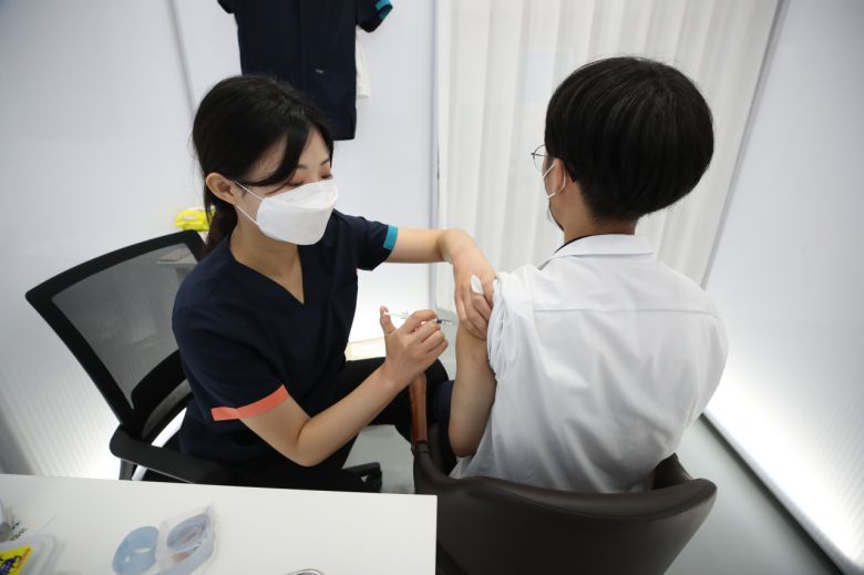 오는 26일부터 시작되는 55~59세에 대한 화이자 백신 접종은 1, 2차 접종 간격이 3주에서 4주로 늘어나게 된다. 사진은 지난 19일 서울 동작구 동작구민체육센터에 마련된 예방접종센터에서 한 고 3 학생이 화이자 백신을 접종받고 있다. [연합]