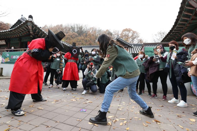 한국민속촌에서 오징어게임에 나오는 딱지치기를 하고 있는 싱가포르 손님들