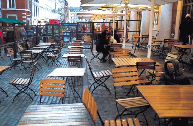 지난 10일(현지시간) 독일 베를린 마우어파크의 한 벽에 그려진 그래피티(벽화)에는 근심스러운 표정을 한 산타클로스와 함께 ‘즐거운 신종 코로나바이러스 감염증(코로나19) & 행복한 새 봉쇄(Lockdown)’란 문구가 담겨 팬데믹(세계적 대유행)으로 고통받는 올해 크리스마스 시즌의 모습을 함축적으로 표현했다(위쪽). 코로나19 하루 신규 확진자 수가 9만명을 넘는 영국에서 18일(현지시간) 런던 한 식당 야외석이 텅 비어 있다. [AP·로이터]