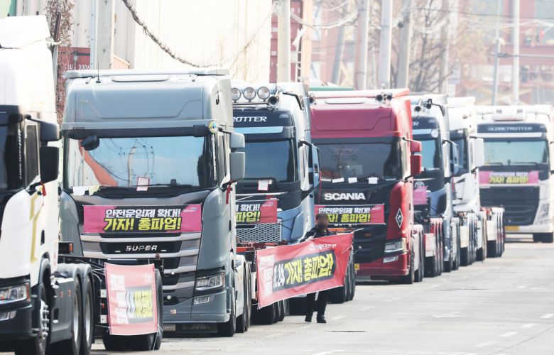 화물연대가 파업을 종료하고 현장 복귀를 결정한 9일 오후 경기도 의왕시 내륙컨테이너기지(ICD) 앞에서 관계자가 도로에 세워둔 화물차들에 붙어있던 파업 관련 현수막을 철거하고 있다. [연합]