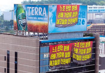 지난 8월 22일 오전 전국민주노동조합총연맹(민주노총) 공공운수노조 화물연대가 점거 농성 중인 서울 강남구 하이트진로 본사 벽면에 ‘노조 탄압 분쇄’, ‘손배 가압류 철회’, ‘해고철회 전원복직’ 등 내용이 담긴 현수막이 걸려 있다. [연합]