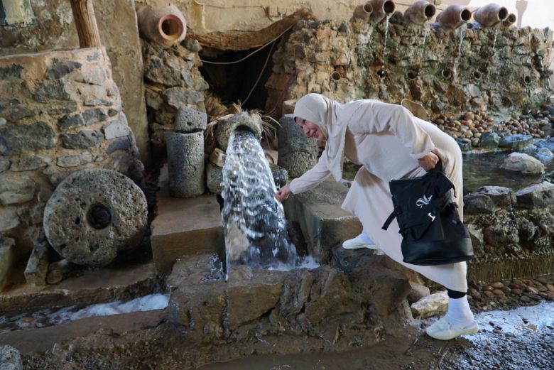 한국인을 닮은 중앙아시아 무슬림 할머니가 데이트팜의 용천수를 손으로 느껴보고 있다.