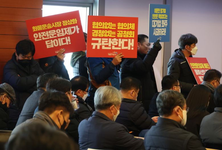 지난달 18일 중구 포스트타워에서 국토부가 주최한 화물운송시장 정상화 방안 공청회에서 화물연대 노조원들이 요구사항 팻말을 들고 있다. [연합]