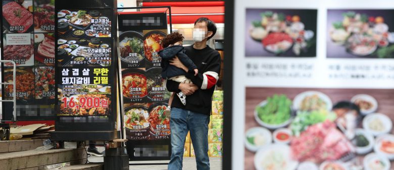 서울 명동 한 거리의 음식점 안내문 앞을 시민이 지나가고 있다.[연합]