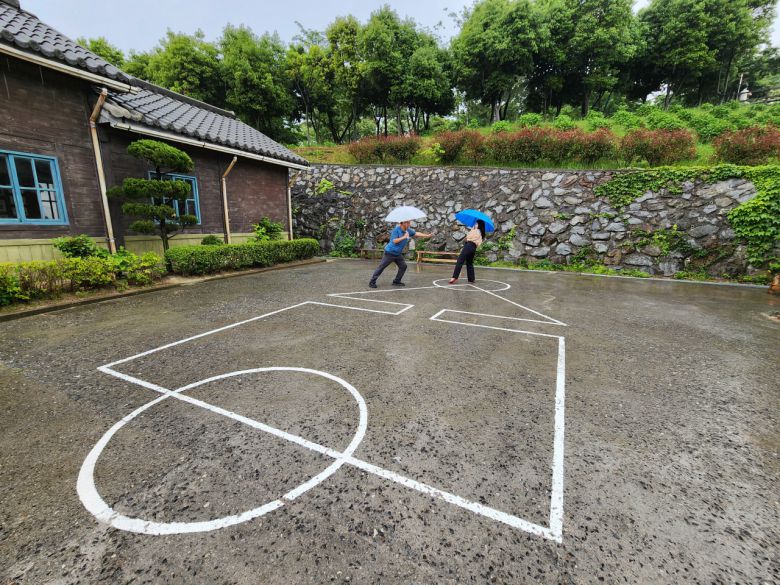 비오는 날 오징어게임하는 모습 설정샷. 오징어게임 드라마가 나오기 몇년전 부터 어른과 아이들이 놀던 곳이다.