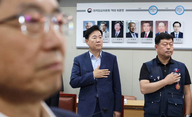 박준식 최저임금위원회 위원장을 비롯한 사용자위원, 근로자위원, 공익위원들이 8일 오후 세종시 정부세종청사 최저임금위원회 회의실에서 열린 제3차 전원회의에 참석해 국기에 경례하고 있다. 연합뉴스