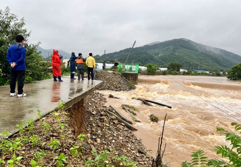 15일 새벽 충청권에 쏟아진 폭우로 충남 청양군 정산면 학암리 하천 둑이 무너지자 군 관계자들이 현장에 나와 피해 상황을 점검하고 있다. [연합]