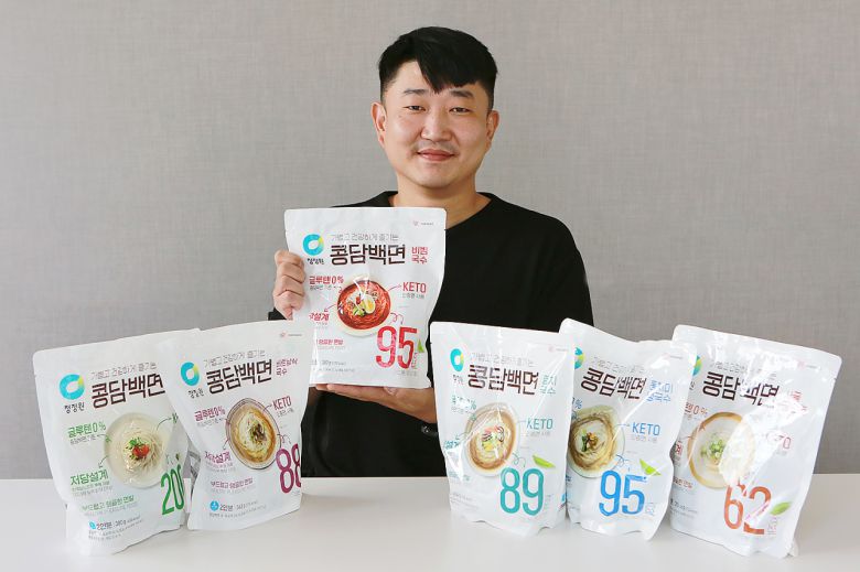 김용건 대상 청정원 식품연구소 수석연구원이 본인이 개발한 콩담백면 제품들과 함께 환하게 미소짓고 있다. 김 연구원이 가장 좋아하는 제품 중 그 중에서도 ‘비빔국수 콩담백면’이라고 한다. [대상 제공]