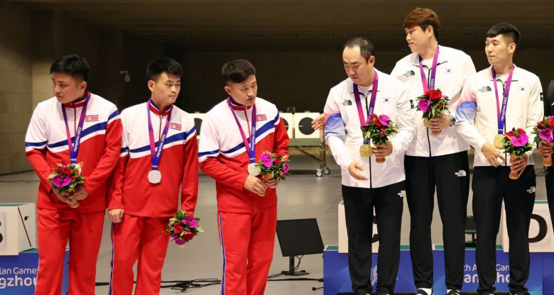 25일 중국 항저우 푸양 인후 스포츠센터에서 열린 제19회 항저우 아시안게임 남자 사격 10m 러닝타깃 단체전에서 금메달을 획득한 한국의 정유진과 선수들이 북한 선수들에게 함께 기념촬영할 것을 요청했지만 은메달을 획득한 북한 선수들이 이에 응하지 않고 있다. [연합]