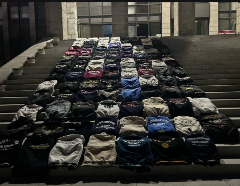 경북대 본관 앞 계단에 학생들이 벗어놓은 학과 점퍼가 줄 맞춰 가지런히 펼쳐져 있다. 재학생들은 금오공대와의 통합에 반대하며 '과잠시위'를 벌이고 있다. [에펨코리아 갈무리]