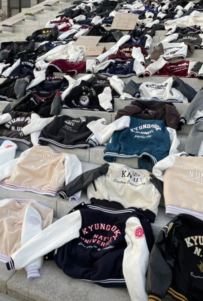 경북대 본관 앞 계단에 학생들이 벗어놓은 학과 점퍼가 가득 펼쳐져 있다. 재학생들은 금오공대와의 통합에 반대하며 '과잠시위'를 벌이고 있다. [에펨코리아 갈무리]