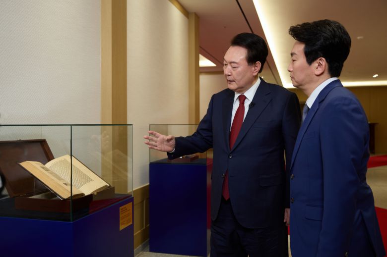 윤석열 대통령이 지난 4일 서울 용산 대통령실 청사에서 가진 KBS '특별대담 대통령실을 가다' 녹화를 마친 뒤 박장범 KBS 앵커에게 지난해 7월 폴란드 공식 방문 선물 교환식에서 두다 폴란드 대통령에게 받은 코페르니쿠스 천문학 저서 '천구의 회전에 관하여'를 소개하고 있다. [연합]