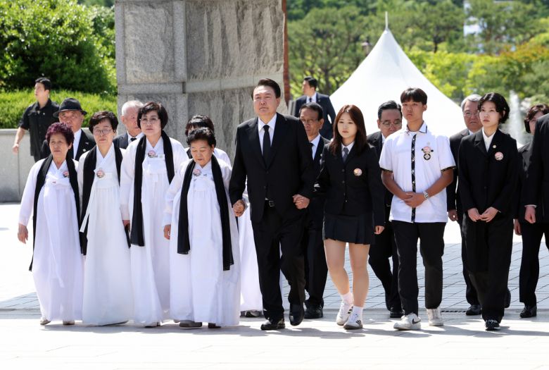 윤석열 대통령이 18일 광주 북구 국립 5·18 민주묘지에서 열린 제44주년 5·18 민주화운동 기념식에서 유족 및 후손들의 손을 잡고 입장하고 있다.[연합]