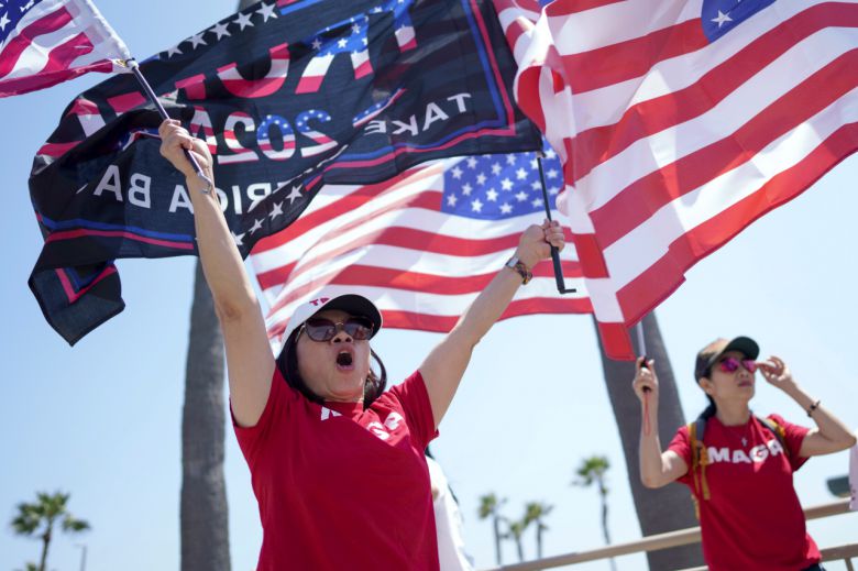 14일(현지시간) 미국 캘리포니아 헌팅턴 비치에서 시민들이 성조기와 함께 도널드 트럼프 전 대통령을 지지하는 내용의 현수막을 흔들며 환호하고 있다. [AP]