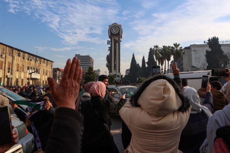시리아 시민들이 서부 주요 도시 홈스의 시계탑을 둘러싸고 시리아 반군의 수도 다마스쿠스 함락을 축하하고 있다. [AFP]