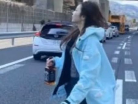 고속도로 위에서 중국인 관광객이 위스키를 손에 들고 가로질러 걷고 있는 모습. [SCMP 갈무리]