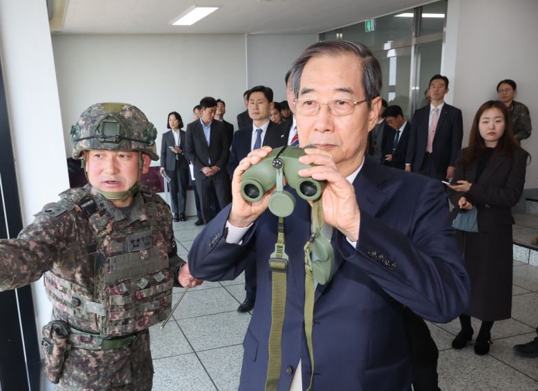 한덕수 전 국무총리가 대통령 권한대행 임무 수행 중 경기도 파주 육군 1사단 도라 관측소(OP) 전망대에서 양진혁 육군 1사단장의 설명을 들으며 전방을 살피는 모습. [연합]