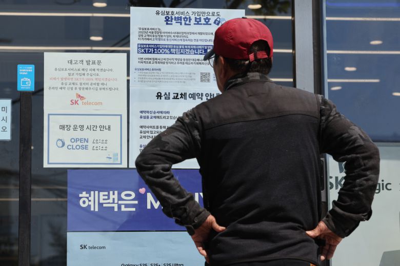 지난 2일 서울 시내의 한 SK텔레콤 대리점 앞에서 한 소비자가 유심 재고 소진 및 유심보호서비스 관련 안내문을 살펴보고 있다. [연합]
