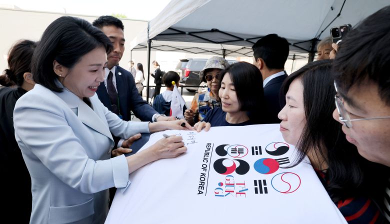 G7 정상회의에 참석하는 이재명 대통령과 함께 캐나다를 방문한 김혜경 여사가 17일(현지시간) 캘거리 한인회관에서 환영나온 주민들의 요청에 티셔츠에 서명하고 있다. [연합]