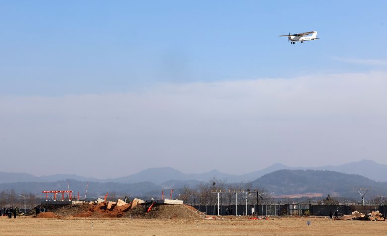 지난 2월 26일 오후 전남 무안국제공항에서 교육용 훈련기가 항공철도사고조사위원회, 경찰, 국과수 관계자들이 현장 조사하고 있는 방위각 시설(로컬라이저) 위를 날고 있다. [연합]