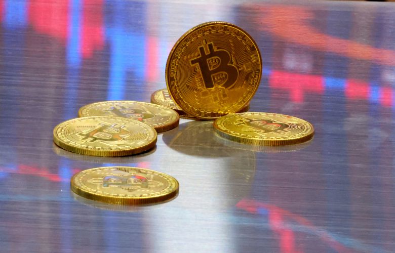 비트코인 모형이 놓인 바닥에 코인 시세 그래프가 비치는 모습. [연합]