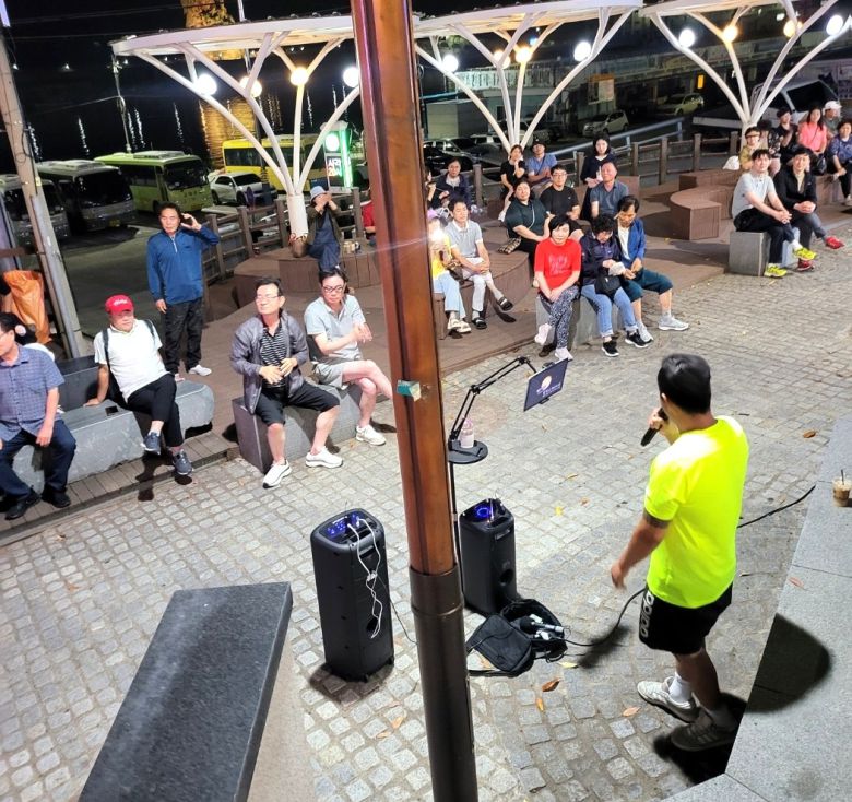 울릉 쿠팡맨으로 알려진 김수현씨가 재능기부 버스킹 공연으로 관광객들이 즐거워 하고 있다.[독자제공]